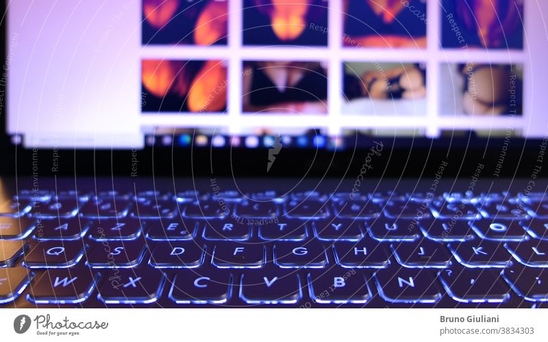 Nahaufnahme auf einer Laptop-Tastatur. Erotische Fotos, die auf dem Bildschirm im Hintergrund erscheinen, sind absichtlich unscharf. Internet Keyboard erotisch