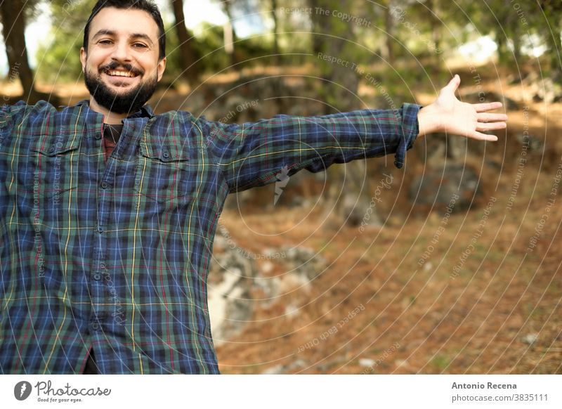 Mann mit Bart und kariertem Hemd eines ästhetischen Holzfällers breitet freudig die Arme inmitten der Natur aus Freiheit Wald kariertes Hemd Vollbart bärtig