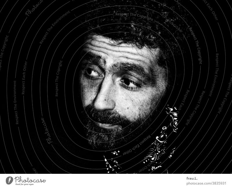Ein skeptischer Mann Locken Bart Halstuch jung Porträt Außenaufnahme attraktiv gutaussehend sitzen nachdenklich ernst