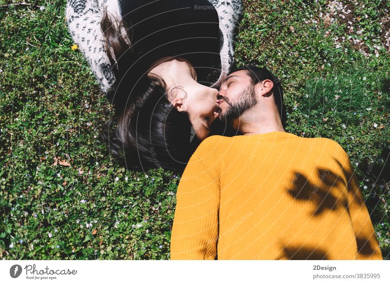 Ein schönes junges Paar liegt auf dem grünen Gras in einer Frühlingswiese in der Draufsicht des Parks. im Freien flirten umarmend Partnerschaft Zusammensein
