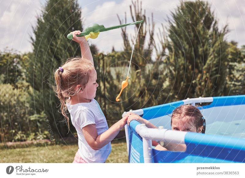 Kinder spielen mit Angelrutenspielzeug in einem Pool im Hausgarten authentisch Hinterhof Kindheit Familie Spaß Garten Fröhlichkeit Glück Freude Lachen Lifestyle