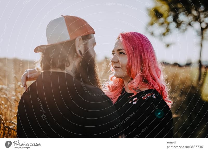 Paare mit Tätowierungen und rosa Haaren umarmen sich und schauen sich an Frau Mann Hipster trendy Kuscheln von Herzen Tattoo Kornfeld Feld Aus Liebe verliebt