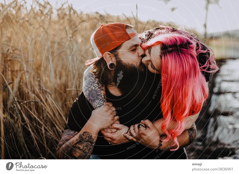 Paar mit Tattoos und pinken Haaren küssen sich Frau Mann Hipster trendy kuscheln innig pinke haare kornfeld Draussen paar liebe verliebt umarmung