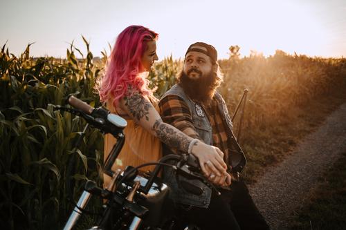 junges Paar mit Tätowierungen und pinken Haaren und Motorrad jugendlich paar liebe verliebt sonnenuntergang Draussen feld pinke haare Tattoo trendy Hipster Mann