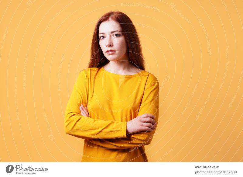 farbenfrohes Studioporträt einer selbstbewussten jungen Frau mit verschränkten Armen Erwachsener Person Menschen gelb orange Farbe Hintergrund schön attraktiv