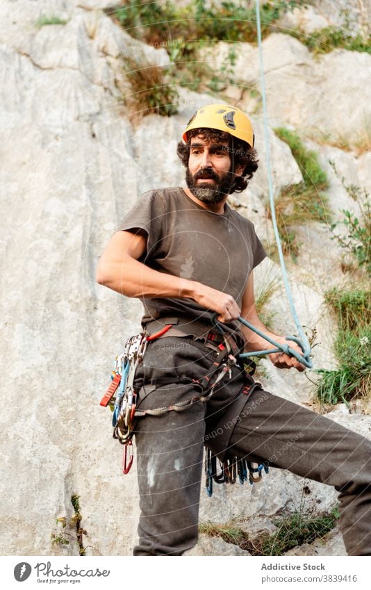 Mann in Sicherheitsgurt in der Nähe von Felsen Aufsteiger Kabelbaum vorbereiten Aufstieg extrem Abenteuer Gerät männlich sicher Karabiner Aktivität