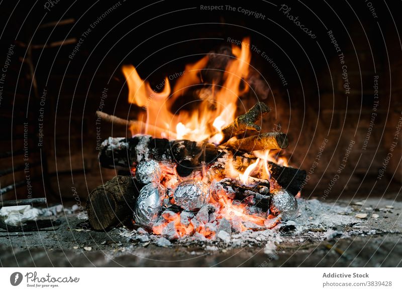 Feuer brennt im Kamin zu Hause Feuerstelle Flamme Schornstein Kartoffel gebacken Folie Aluminium lecker vorbereiten rustikal Brandwunde erwärmen heiß warm