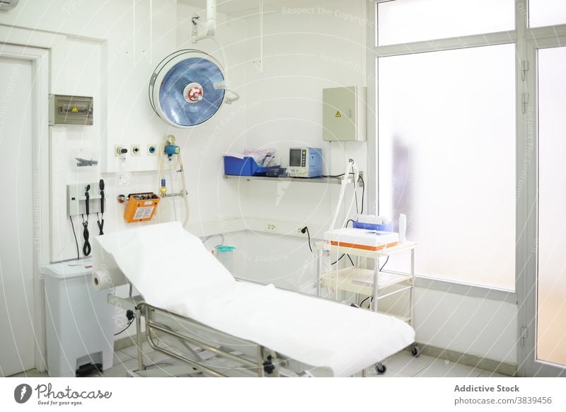 Medizinische Liege in der Nähe von professionellen Geräten in der Klinik medizinisch Werkzeug kreativ Design Arbeitsplatz Lampe Handwagen weiß Farbe Schot