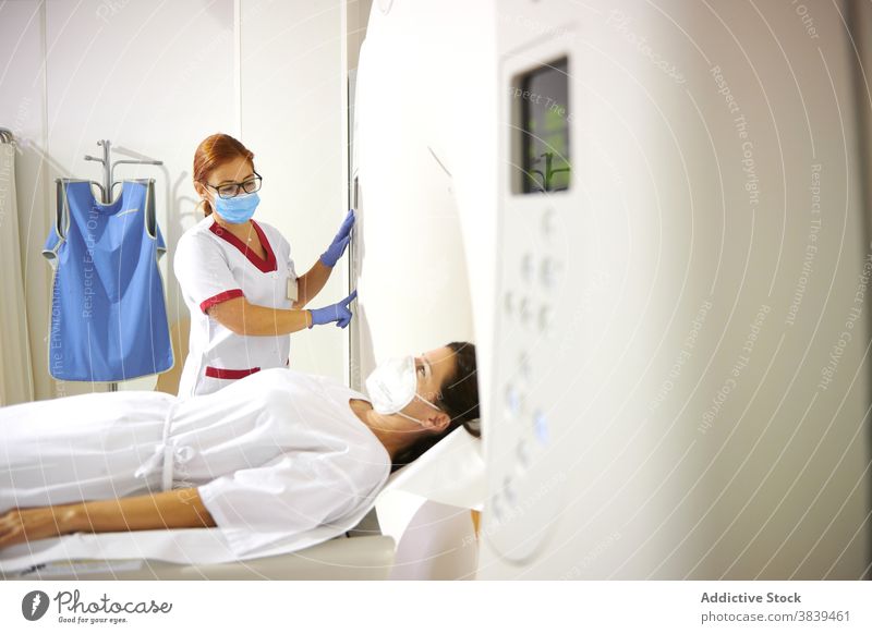 Unbekannter Radiologe und Patient am Tomographiegerät in der Klinik Radiologin geduldig Gerät Diagnostik Gesundheitswesen Uniform Mundschutz professionell