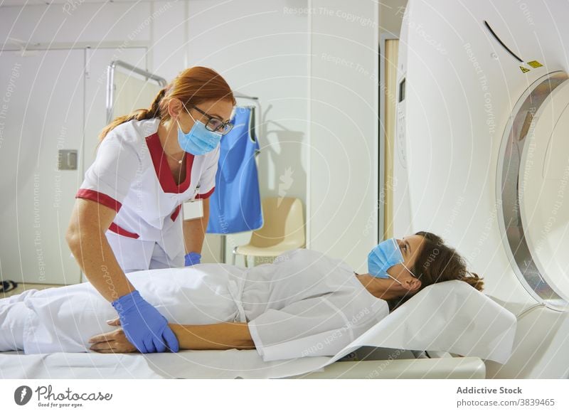 Radiologe und Patient am Tomographiegerät in der Klinik Radiologin geduldig Gerät Diagnostik Gesundheitswesen Uniform Mundschutz professionell Frauen