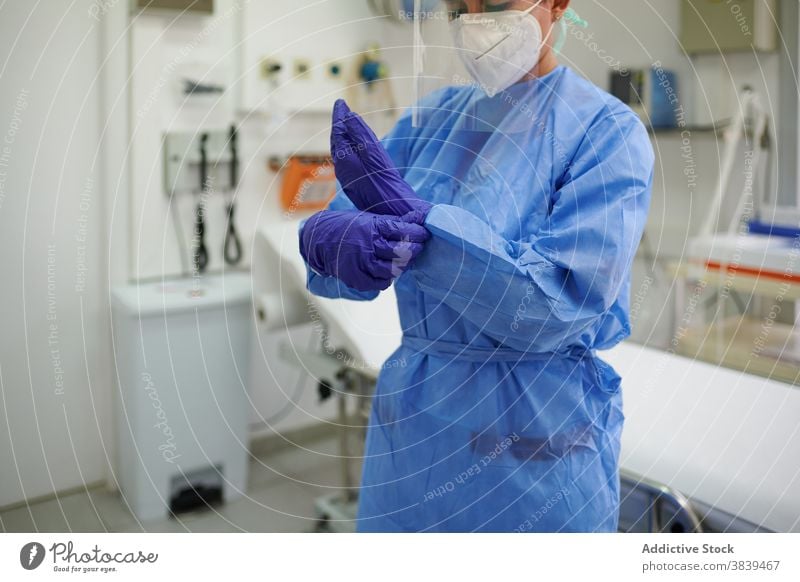 Anonymer Arzt in Uniform zieht sterile Handschuhe an angezogen Job Prozess Gerät medizinisch Klinik Frau Sanitäter Mundschutz Atemwegserkrankungen Krankenhaus