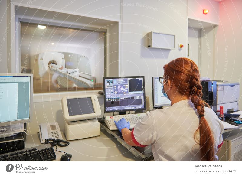 Unkenntlicher Radiologe bei der Arbeit am Computer während der Tomographie-Diagnostik in der Klinik Radiologin Prüfung Monitor Prozess Gerät geduldig benutzend