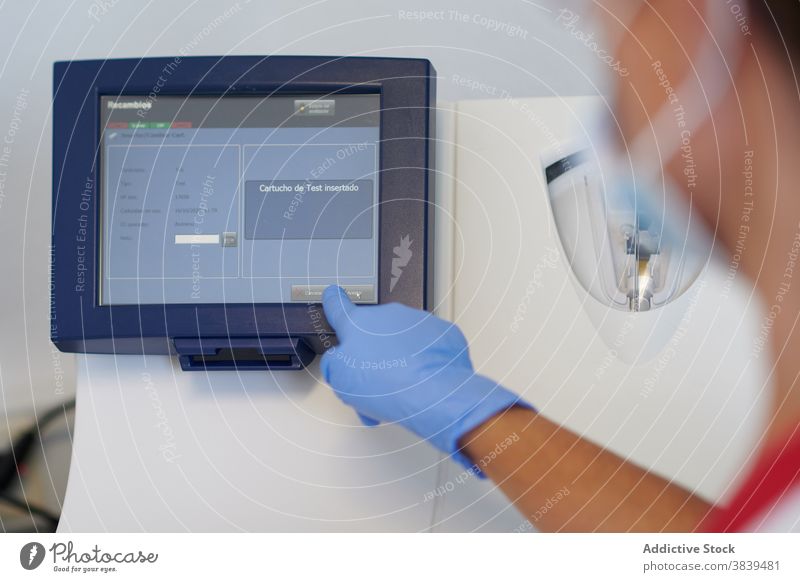 Crop-Arzt mit medizinischem Diagnosegerät in der Klinik Diagnostik Gerät Monitor wählen Option modern professionell Labor Zentrum Analyse Handschuh steril