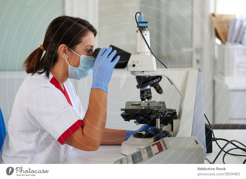 Anonyme Wissenschaftlerin arbeitet mit Mikroskop im Labor Spezialist Arbeit Analyse Diagnostik Prüfung medizinisch Gerät Prozess Frau Beruf Uniform benutzend