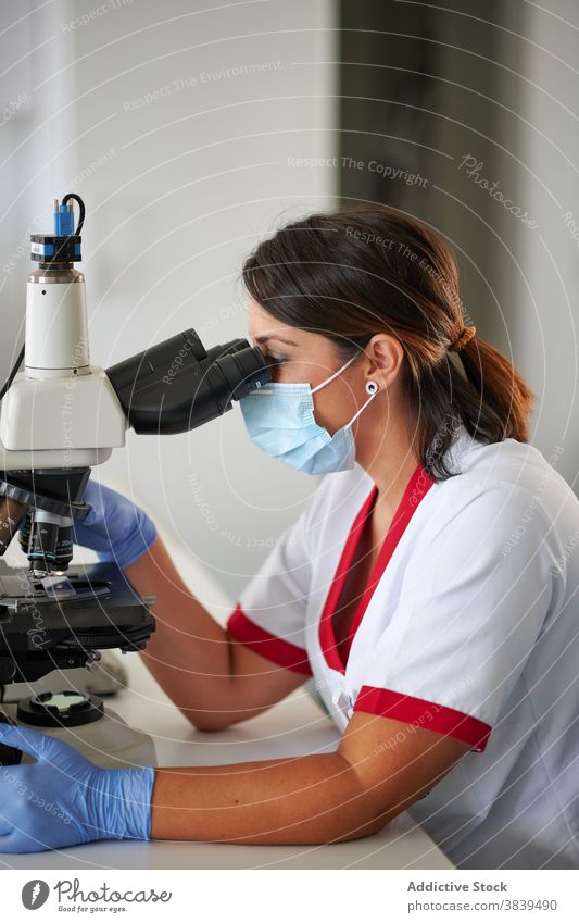 Weibliche Wissenschaftlerin arbeitet mit Mikroskop im Labor Spezialist Arbeit Analyse Diagnostik Prüfung medizinisch Gerät Prozess Frau Beruf Uniform benutzend