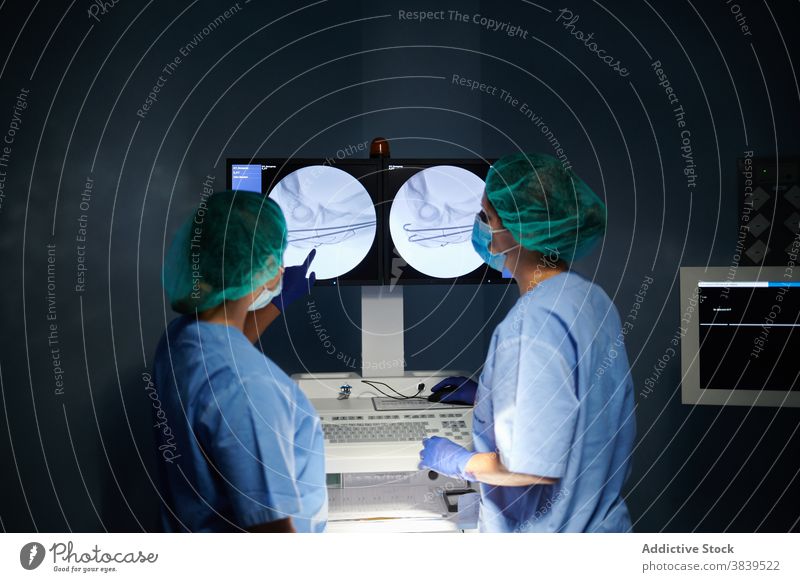 Unkenntlich gemachte Ärzte, die bei der Arbeit auf den Monitor eines Diagnosegeräts zeigen Sanitäter Punkt Gerät Diagnostik Anzeige Bild medizinisch Uniform