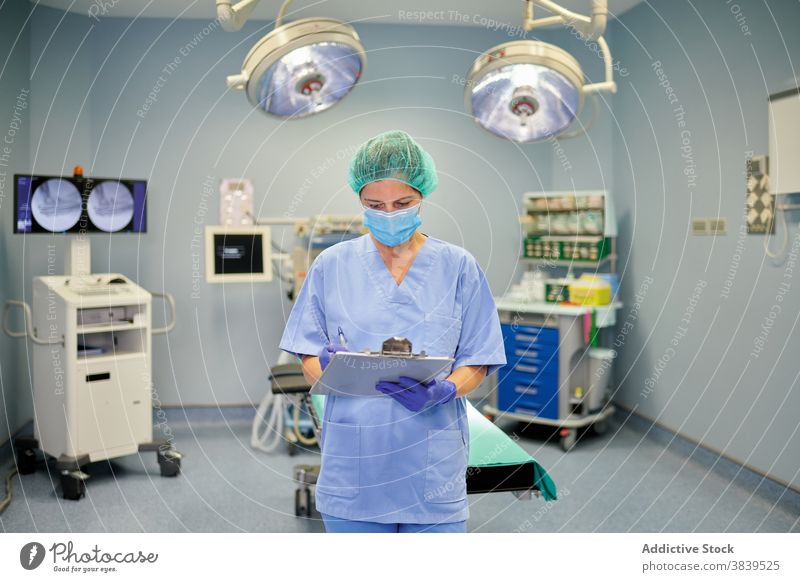 Unerkennbarer Arzt in Uniform beobachtet Papiere im Krankenhaus Sanitäter interagieren Kollege Kommunizieren Job Frau Gerät professionell zuschauend Lampe