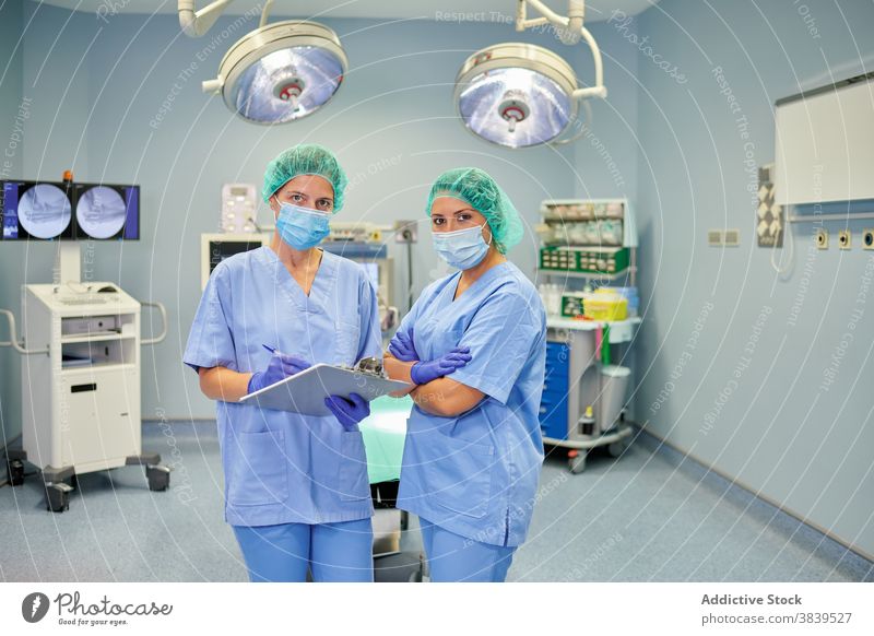 Nicht erkennbare Ärzte in Uniformen beobachten Papiere im Krankenhaus Sanitäter interagieren Kollege Kommunizieren Job Frauen Gerät professionell zuschauend