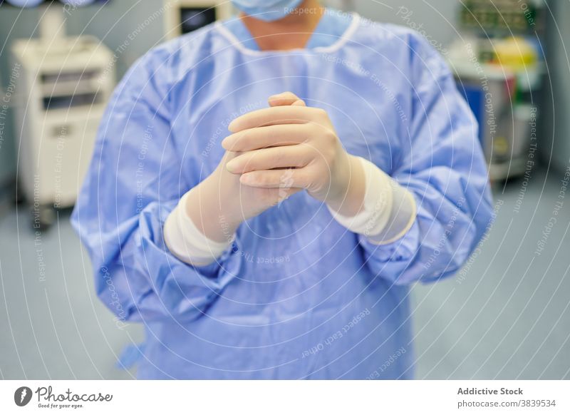 Unerkannt fokussierter Arzt in Uniform in der Klinik Sanitäter Beruf Spezialist Fokus medizinisch Gerät Hände gefaltet Frau steril Mundschutz schützend Job