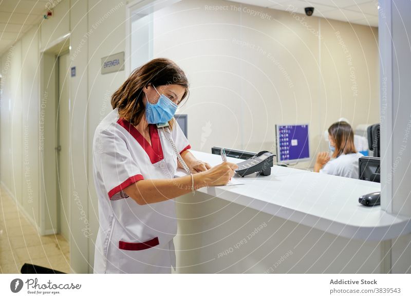 Weiblicher Arzt beim Unterschreiben von Dokumenten in der Nähe der Klinikrezeption Frau Zeichen zur Kenntnis nehmen Krankenpfleger Rezeption Personal