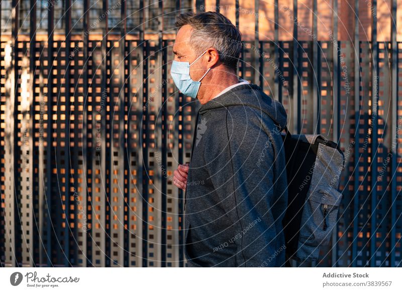 Älterer pensionierter Mann mit Gesichtsmaske und Sportkleidung, der die Straße entlanggeht 58 ruhen Rhythmus Gesundheitswesen Fitness Bluthochdruck Training