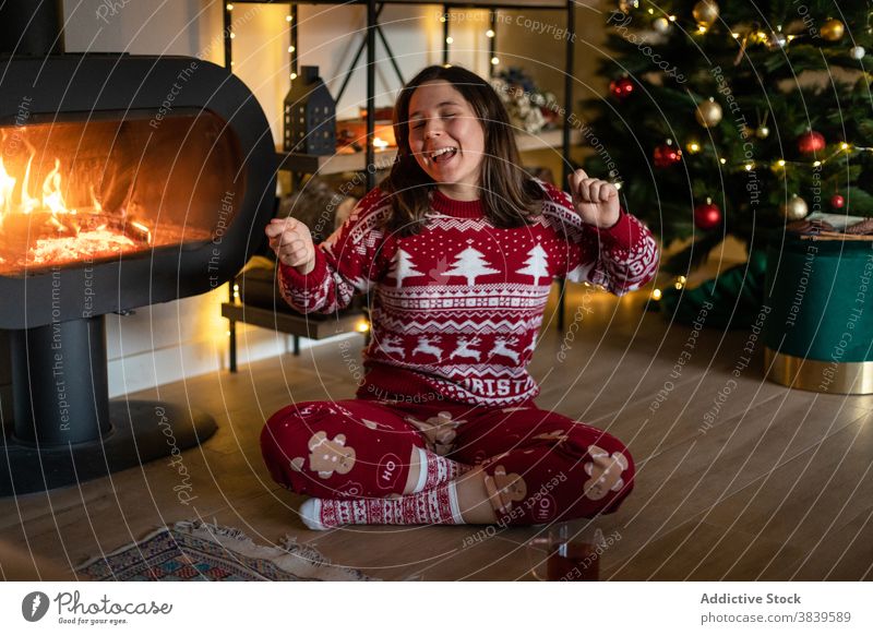 Fröhliche Frau im gemütlichen Weihnachtspulli singt zu Hause Weihnachten Gesang singen Feiertag Schornstein sich[Akk] entspannen Atmosphäre fröhlich Vorabend
