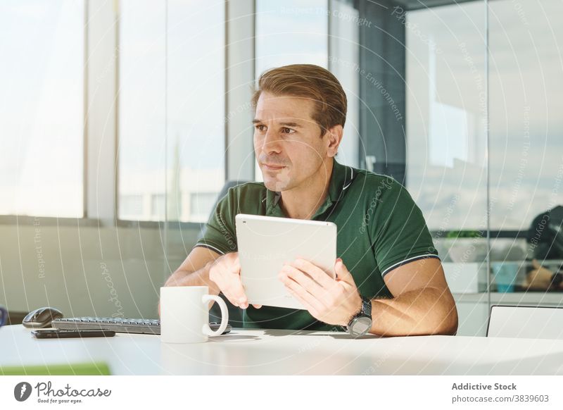 Fokussierter Mann mit Tablet im Büro Browsen Tablette Programmierer Entwickler Arbeit Programmierung Entwicklung benutzend männlich Tisch Arbeitsplatz modern