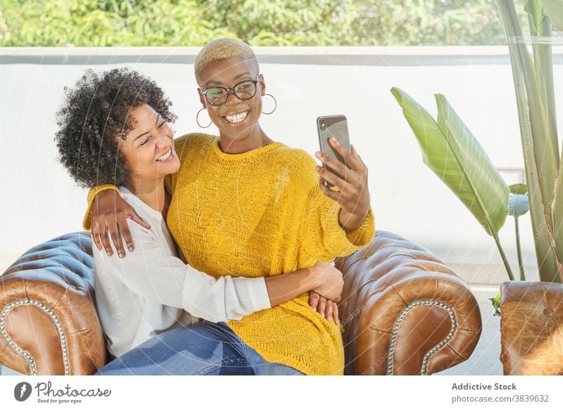 Entzücktes schwarzes lesbisches Paar, das ein Selfie auf dem Smartphone macht Frauen Liebe lgbt Selbstportrait Umarmung gleich ethnisch Afroamerikaner Mobile