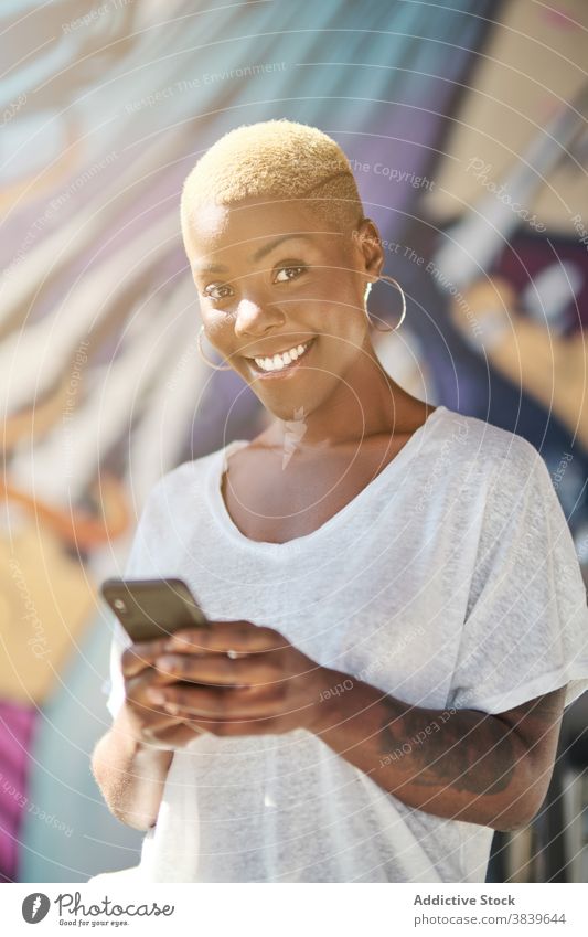 Fröhliche schwarze Frau auf Smartphone Selbstportrait heiter sich[Akk] entspannen Spaß haben sonnig Café benutzend ethnisch Afroamerikaner Lächeln modern