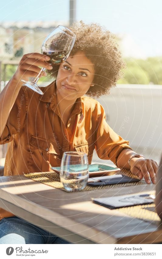 Schwarze Frau mit Weinglas im Restaurant untersuchen trinken Glas Alkohol Tisch Café Afroamerikaner schwarz ethnisch Getränk sich[Akk] entspannen sitzen ruhen