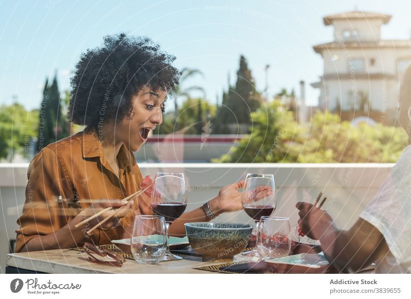 Aufgeregte schwarze Frauen essen Sushi im Restaurant Asiatische Küche Wunder Überraschung erstaunt wow Tisch sich[Akk] entspannen ethnisch Afroamerikaner sitzen