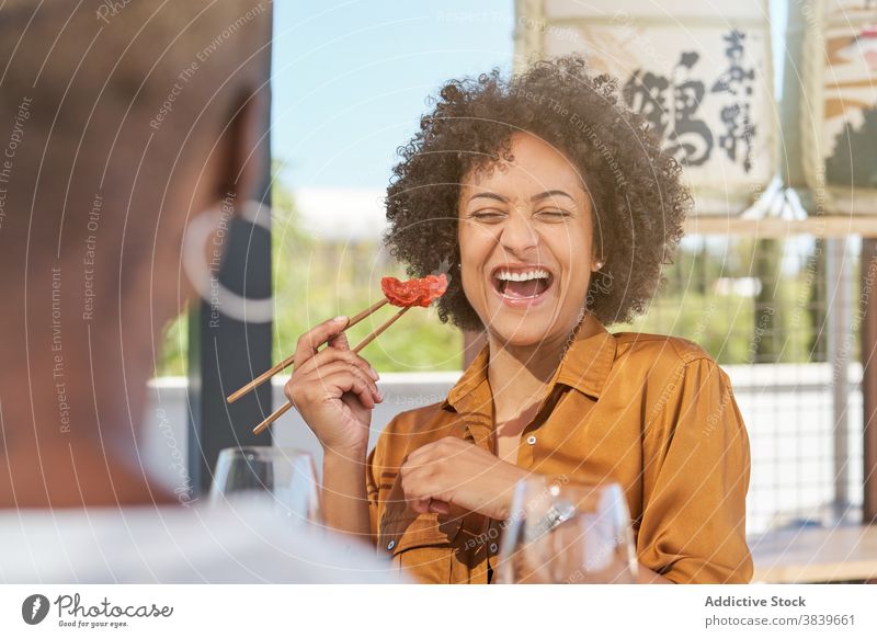 Playful ethnischen Frauen haben Spaß beim Essen Sushi Tisch im Restaurant Essstäbchen Spaß haben Lachen kindisch spielen heiter Freundschaft Lebensmittel