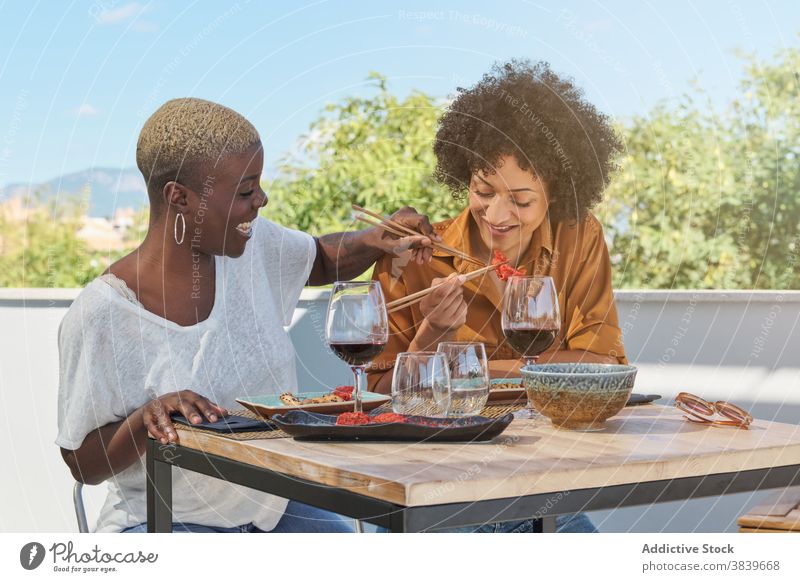 Playful ethnischen Frauen haben Spaß am Tisch im Restaurant Essstäbchen Spaß haben Lachen kindisch spielen heiter Freundschaft Lebensmittel schwarz