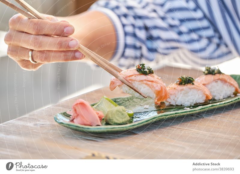 Anonyme Person isst leckere Sushi Nigiri auf einem Teller im Cafe Reis Lachs Asiatische Küche Restaurant Meeresfrüchte Orientalisch Tradition Fisch