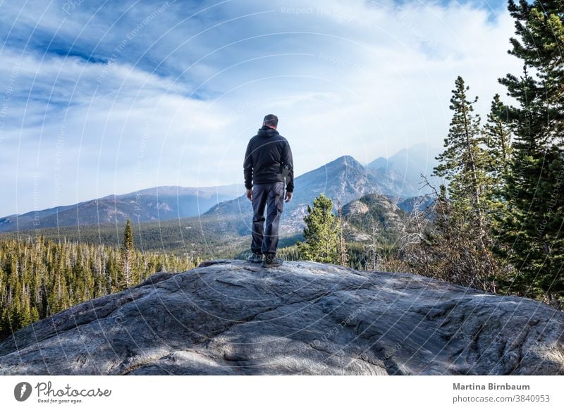 Mann steht auf einem Gipfel im Rocky Mountain-Nationalpark und beobachtet den Rauch der Waldbrände, die in das Tal kommen Tourist Wanderer caucasina