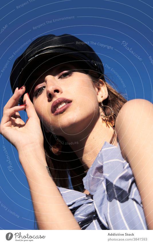 Selbstbewusste Frau mit Lederkappe an einem sonnigen Tag Verschlussdeckel Kopfbedeckung Stil Material modern trendy Sommer Model Kleid Outfit blau Himmel Stoff