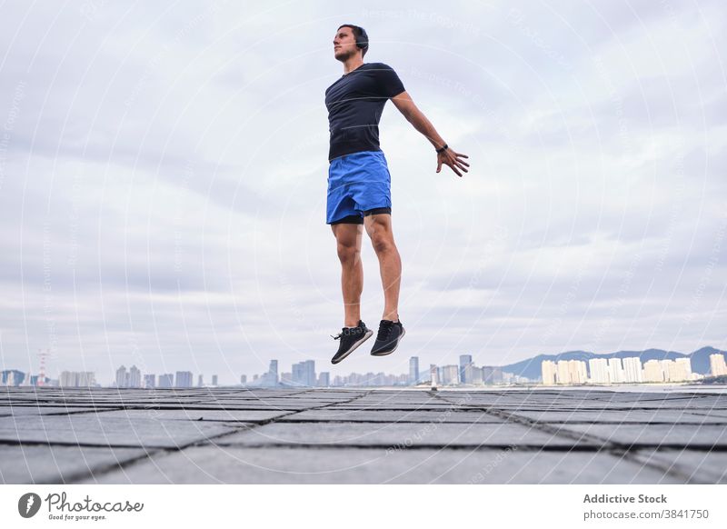 Aktiver Sportler springt beim Training in der Stadt Läufer Aufwärmen springen aktiv Herz Sprung Straße Großstadt männlich Athlet Fitness Energie Körper Übung