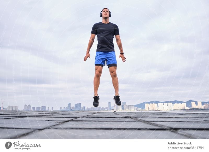 Aktiver Sportler springt beim Training in der Stadt Läufer Aufwärmen springen aktiv Herz Sprung Straße Großstadt männlich Athlet Fitness Energie Körper Übung