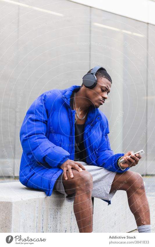 Schwarzer Mann mit Kopfhörer auf Smartphone in der Stadt zuhören Musik Windstille Gesang Drahtlos Großstadt Straße männlich ethnisch schwarz Afroamerikaner
