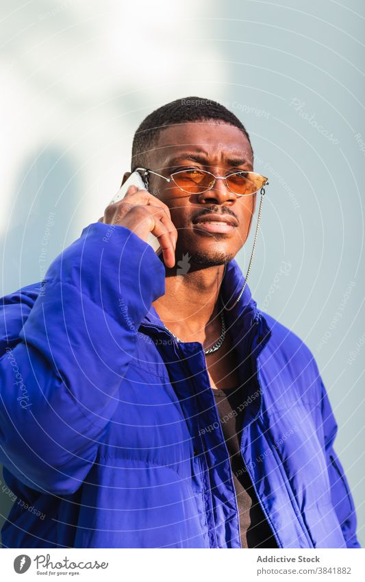 Trendiger schwarzer Mann am Smartphone in der Stadt Stil cool Hipster Bestimmen Sie benutzend trendy männlich ethnisch Afroamerikaner warm blau Jacke Straße