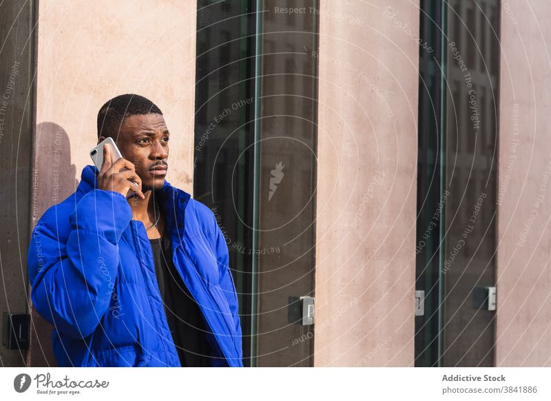 Ernster ethnischer Mann, der in der Stadt auf einem Smartphone spricht Telefonanruf Anruf reden sprechen Gespräch Großstadt Stil urban männlich schwarz