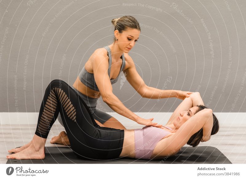 Schlanke Frau macht Yoga unter Kontrolle des persönlichen Instruktors Personal Ausbilderin Frauen üben Asana Pose abstützen Atelier Achtsamkeit Dehnung hell