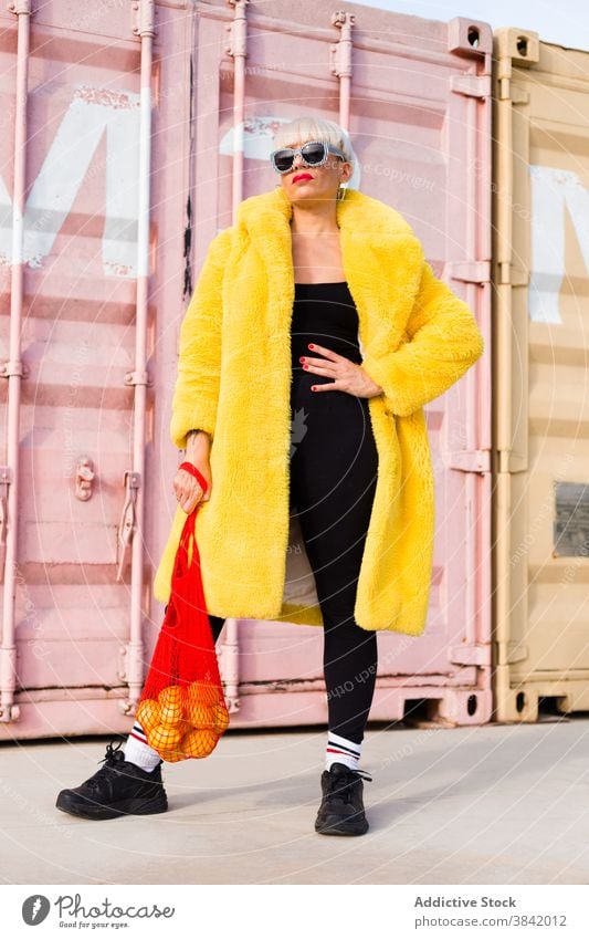 Stilvolle Frau in lebendiger Kleidung auf der Straße Hipster lebhaft Outfit stehen hell Sack umweltfreundlich orange pulsierend Farbe Großstadt modern cool Mode