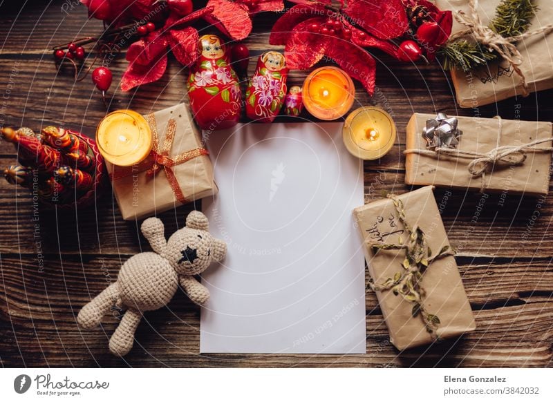 Weihnachtsmuster für Postkarte mit Bastelpapier, Geschenkkarton, handgemachtem Weihnachtsspielzeug und Kerzen. Draufsicht auf Holztisch. Ornament und Weihnachtsgeschenk. Weihnachtsmann-Brief.