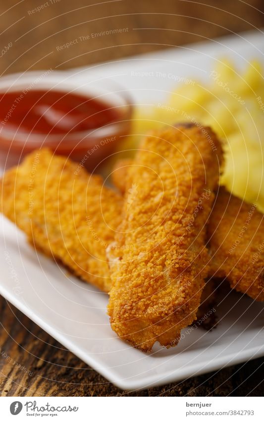 Fischstäbchen mit Kartoffelsalat auf dem Teller Brotkrumen Stil Vorspeise Fischfinger Hintergrund Nahaufnahme braun Kindermenü gegrillt golden fischstaebchen
