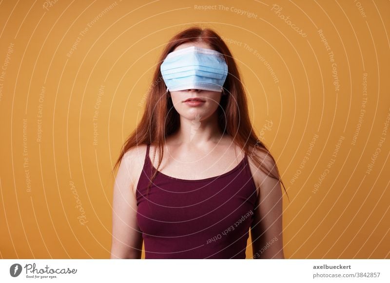 junge Frau, die Mundschutz Maske über den Augen trägt - Corona-Leugner Gesichtsmaske Korona-Verweigerer COVID Coronavirus leugnen blind falsch protestieren
