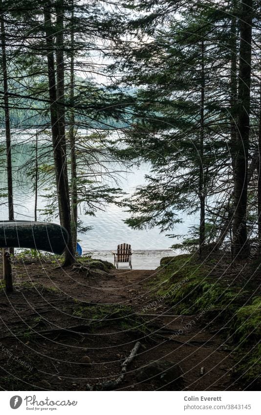 Adirondack Chair am See mit Kanu im Vordergrund adirondack-Stuhl entspannend Abenteuer Kanutour Sommer Ferien & Urlaub & Reisen Natur Wasser Tag