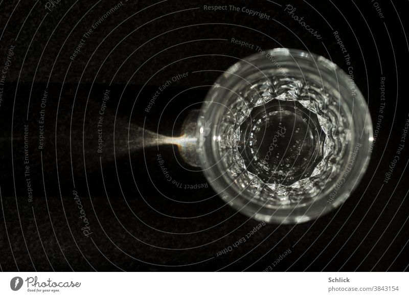 Wasserglas made in France mit Sprudel in Vogelperspektive glänzt im Seitenlicht auf dunklem Untergrund Text glänzen dunkler Hintergrund Granit Gasblasen