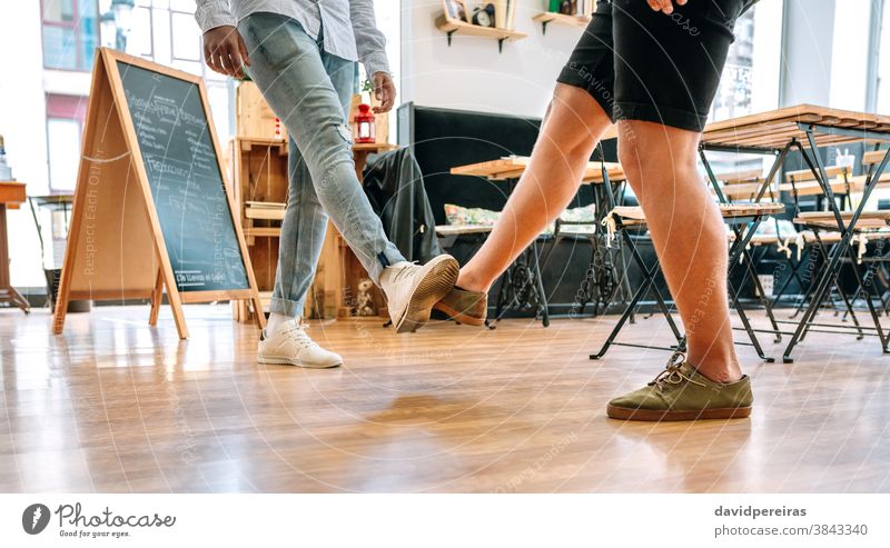 Zwei nicht wiedererkennbare Freunde salutieren mit den Füßen unkenntlich Beinhöcker Coronavirus Fuß Gruß soziale Distanzierung covid-19 unsicher vermeiden