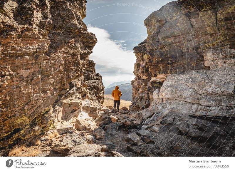 Mann steht auf einem Gipfel zwischen Felsen im Rocky Mountain-Nationalpark und schaut an einem kalten und windigen Tag über die Bergkette Reisender Winter
